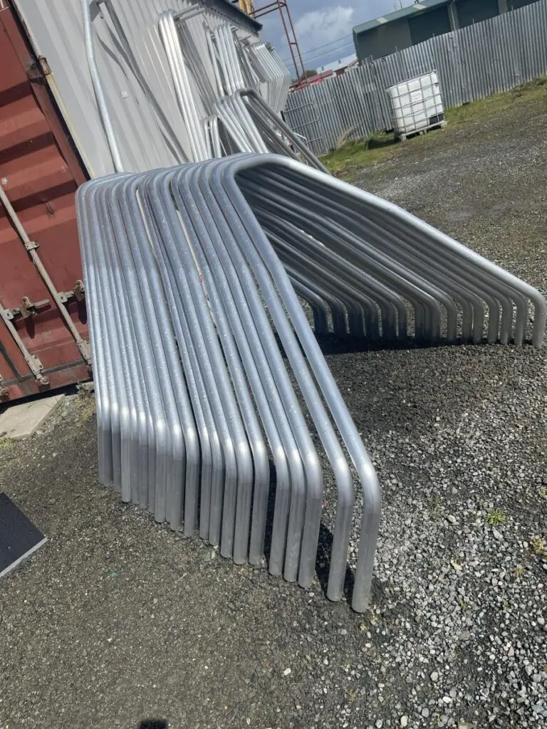 A batch of identical bent aluminium tube hoops stacked outside the Probend workshop