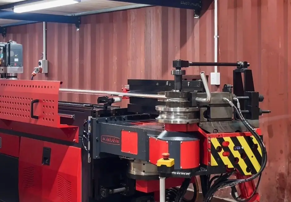 Probend's red Akyapak CNC tube bender in the Invercargill workshop with a freshly bent tube on the bending head