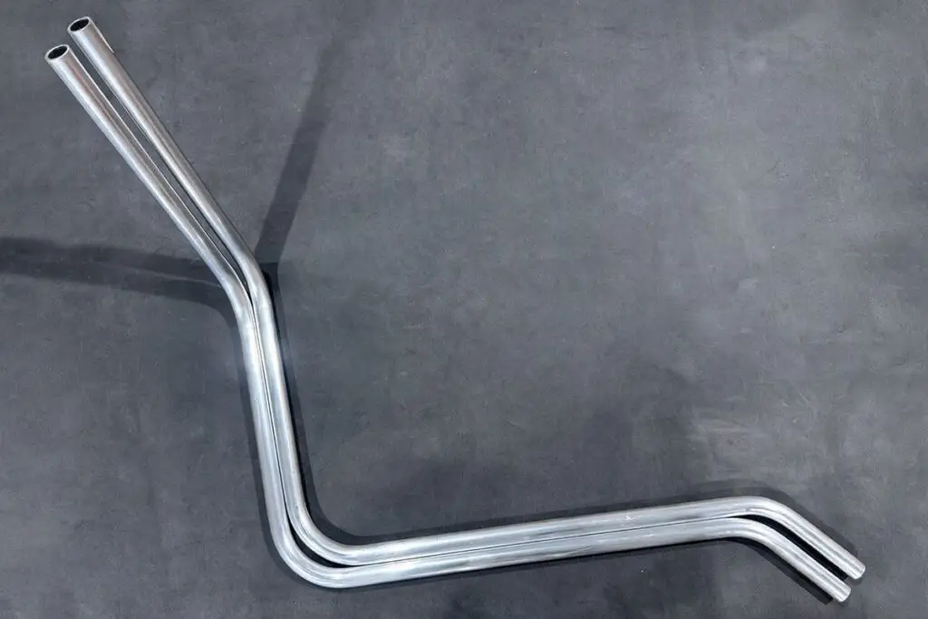 A pair of identical bent aluminium tubes on a dark background