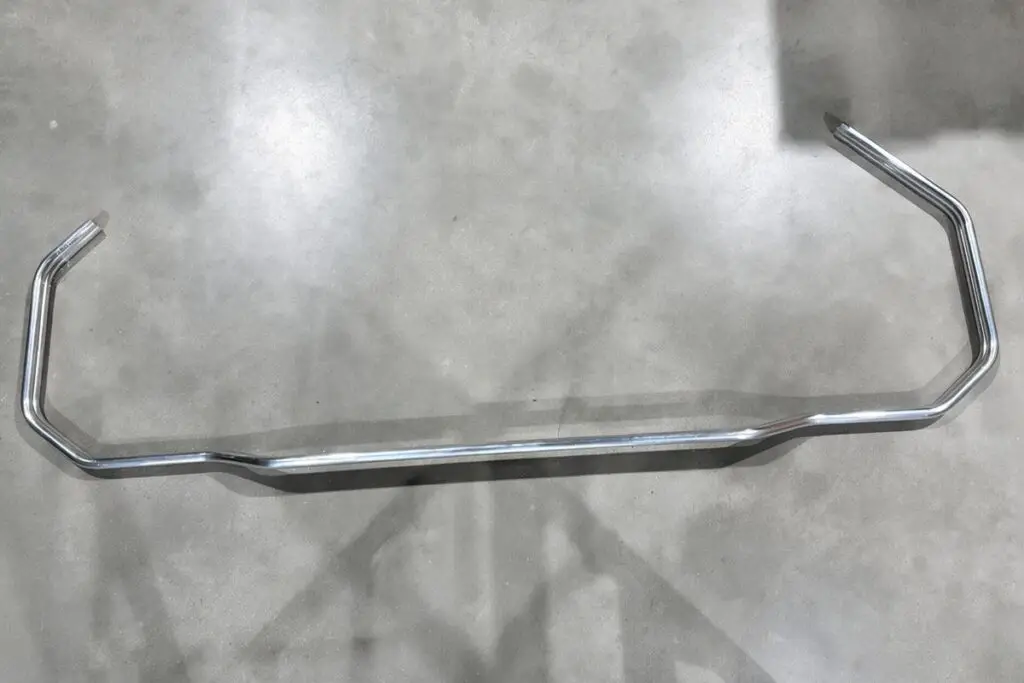 Polished aluminium rail with several bends and offsets on a concrete floor